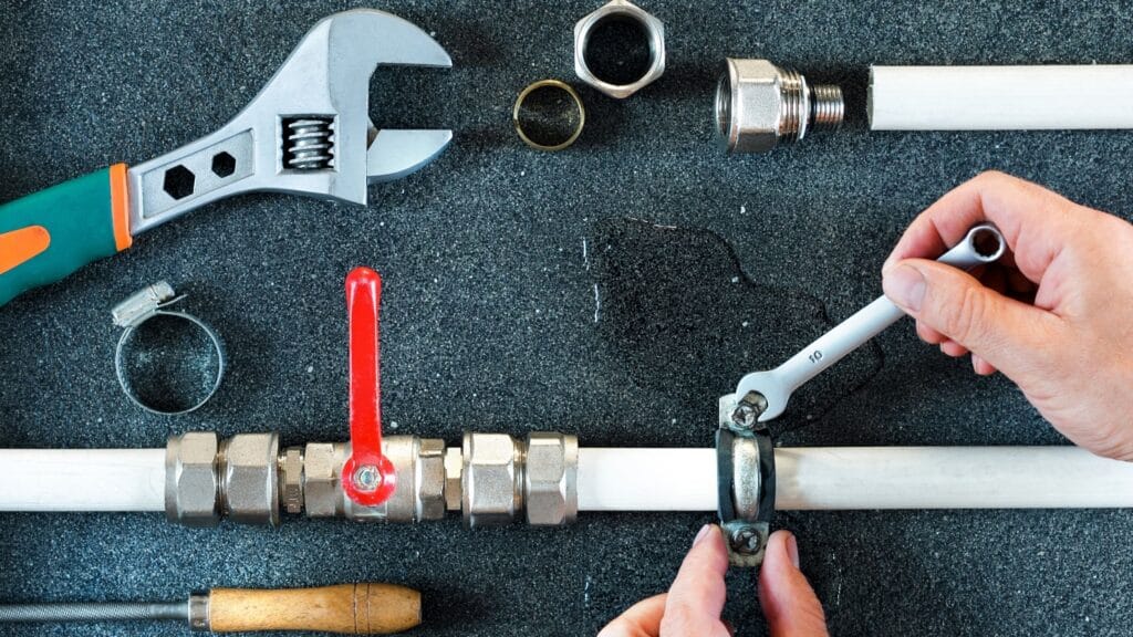 Plumber repairing a pipe valve with an adjustable wrench in Louisville
